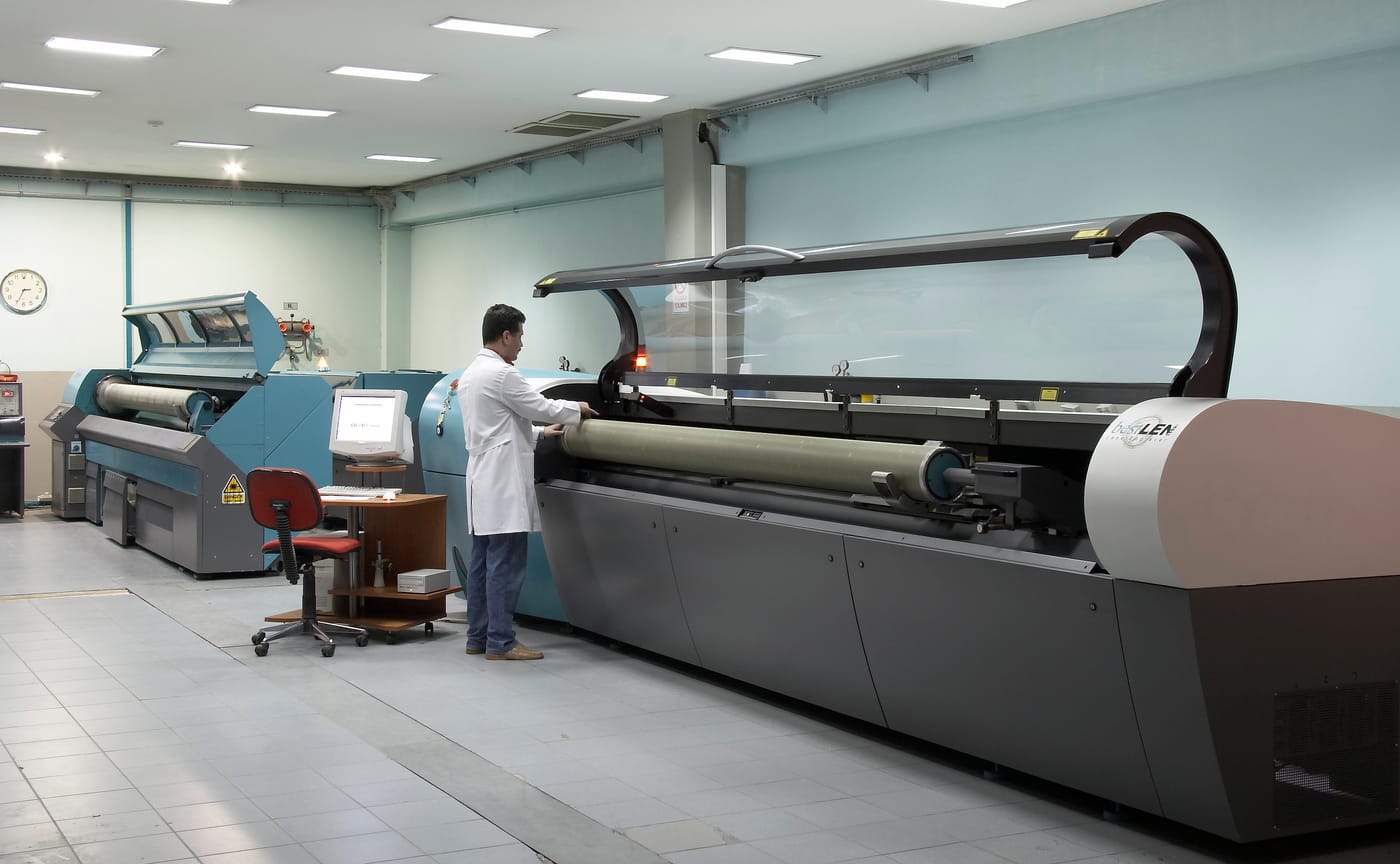 Lazer gravür salonu, sıralı makineler ve çalışan teknisyenler